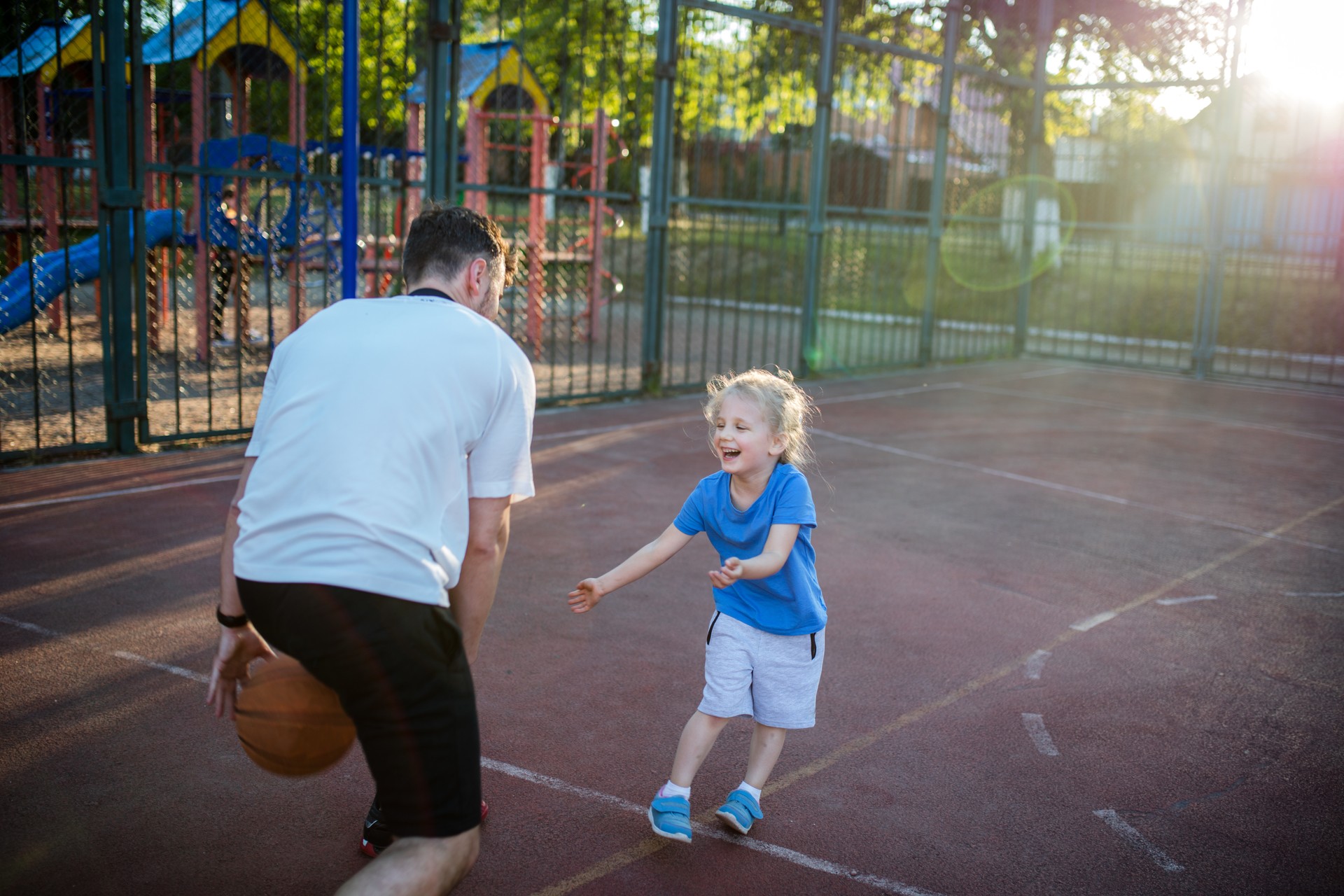 Giovane padre millenario che gioca a basket con la sua bambina